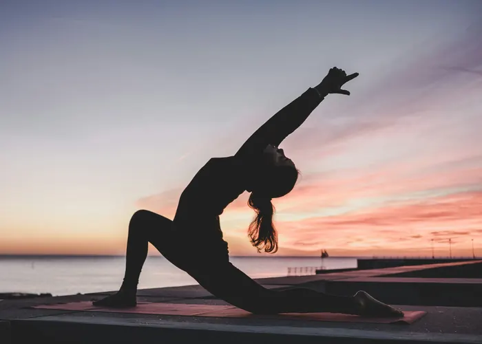 Silhouette of a woman in a low lunge at sunset